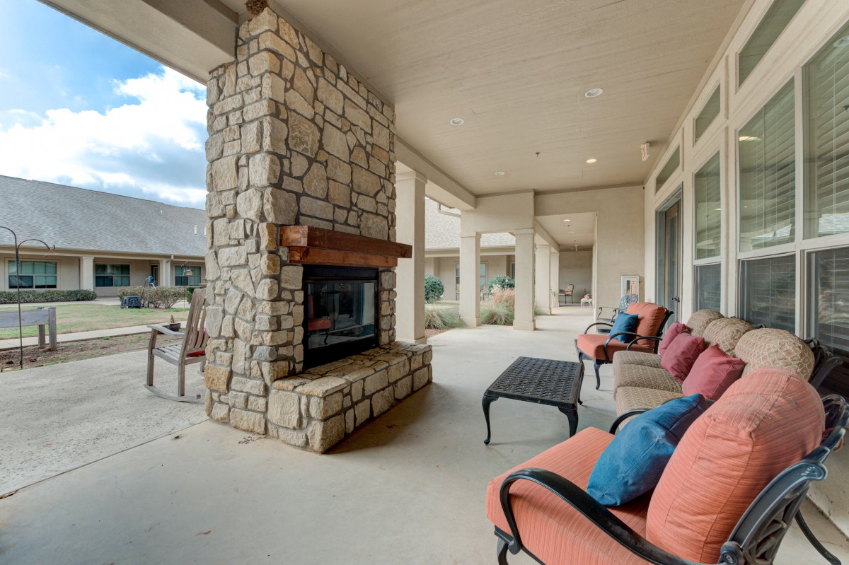 A cozy outdoor patio featuring a stone fireplace, comfortable seating with cushions, and a coffee table.