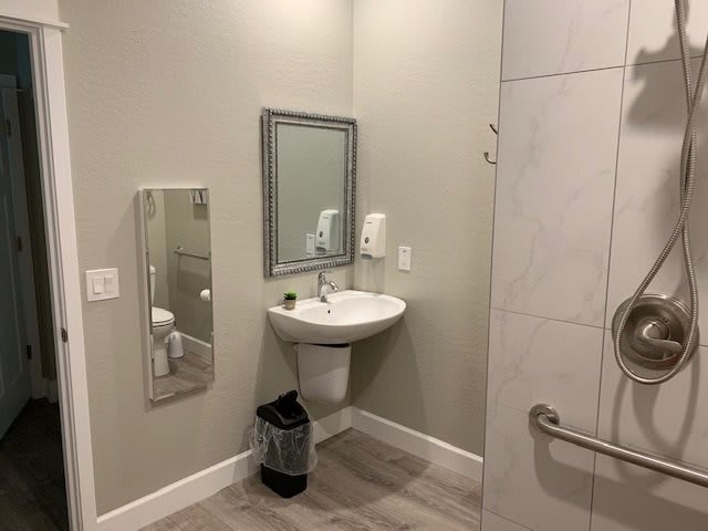 A clean and modern bathroom with a sink, mirror, hand dryer, and waste bin.