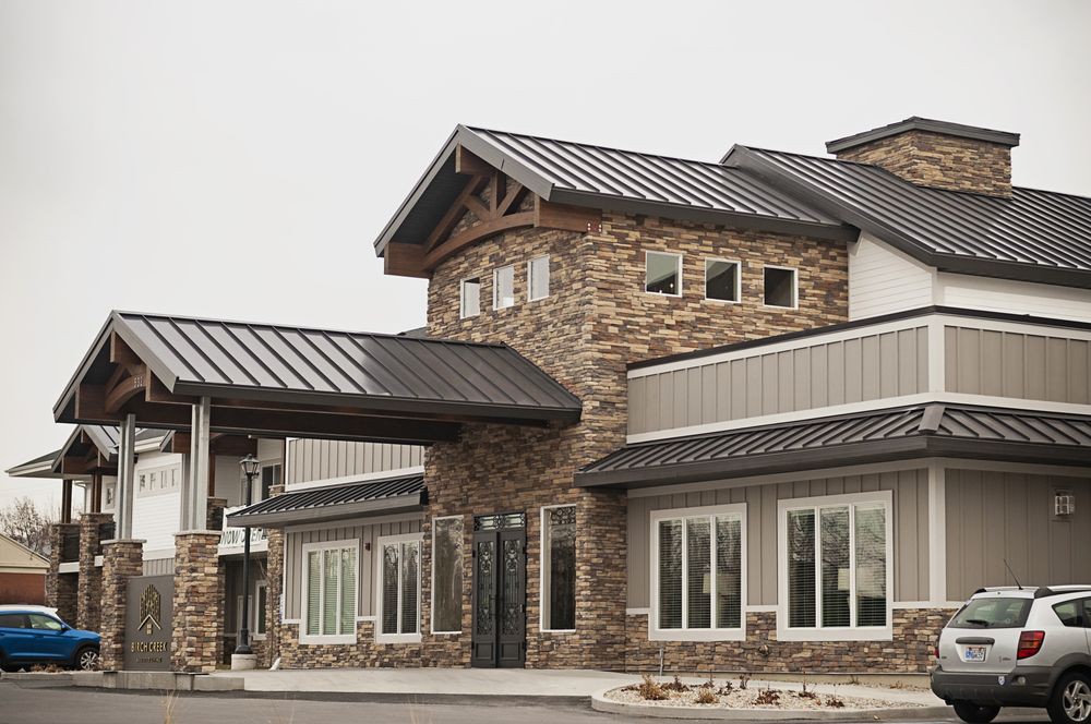 A modern commercial building with a stone facade and metal roof.