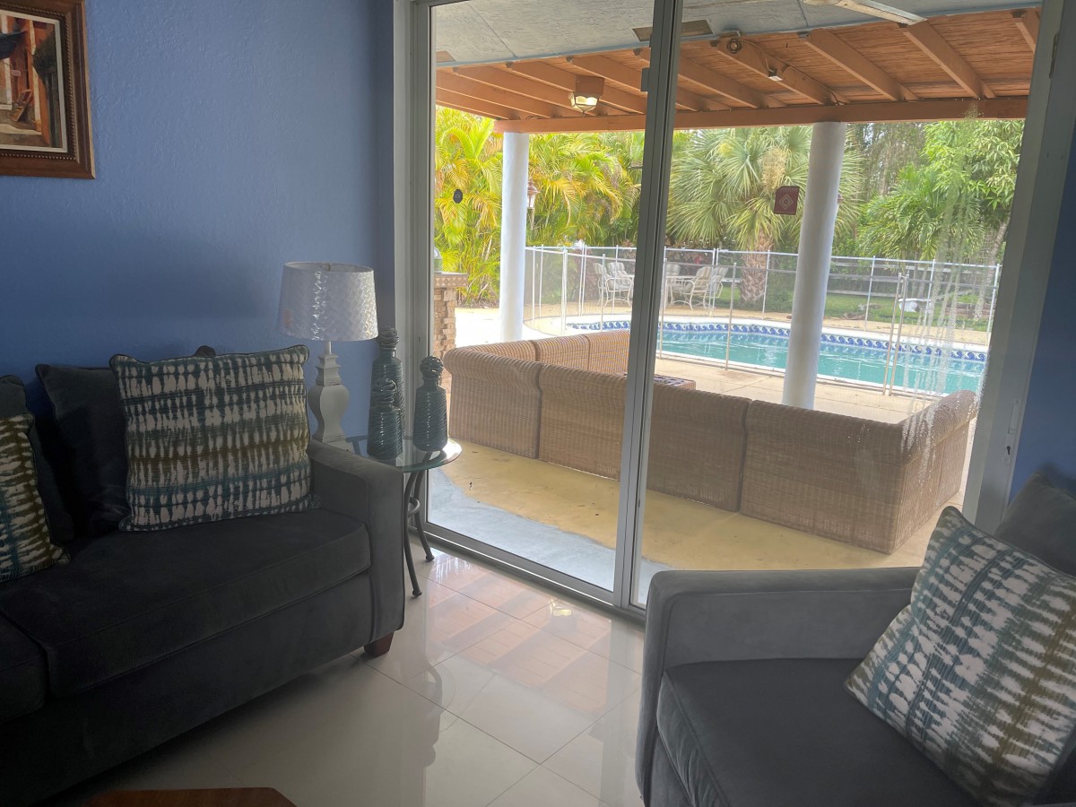 A cozy living room with a view of the pool through sliding glass doors.