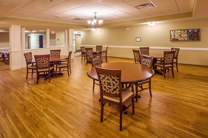 An empty dining room with wooden tables and chairs arranged neatly on a hardwood floor.