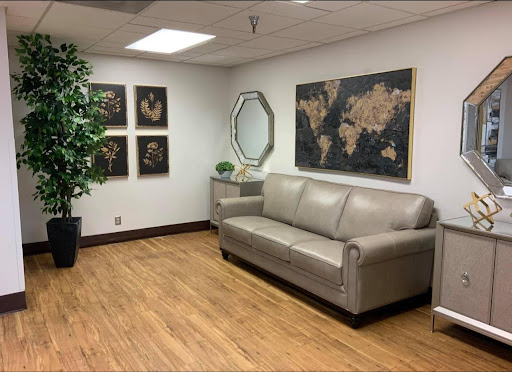 A cozy office waiting area featuring a comfortable sofa, decorative artwork, and greenery.