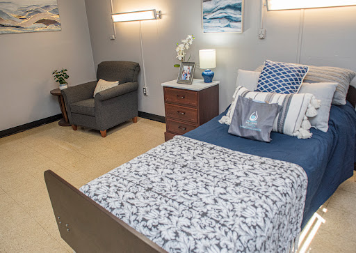 A cozy bedroom setup featuring a comfortable bed, a reading chair, and decorative elements.