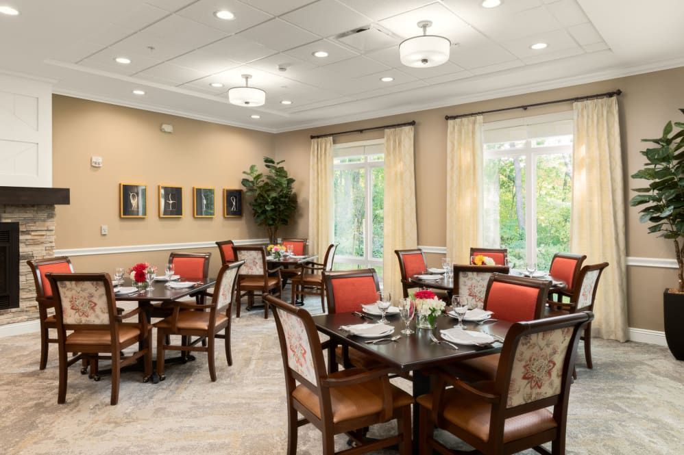 An elegantly designed dining room with neatly arranged tables and chairs, soft lighting, and large windows.