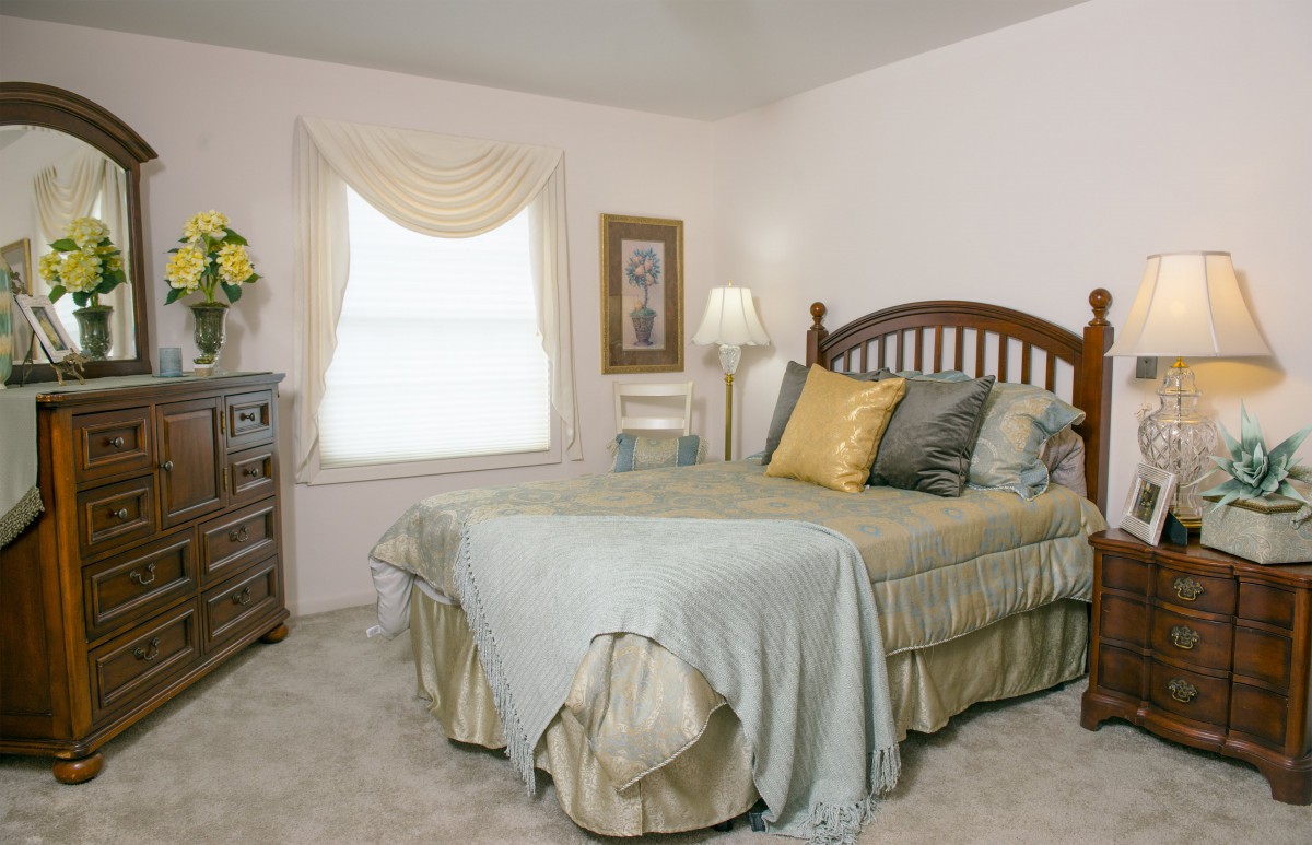 A cozy bedroom with a neatly made bed and a window letting in natural light.
