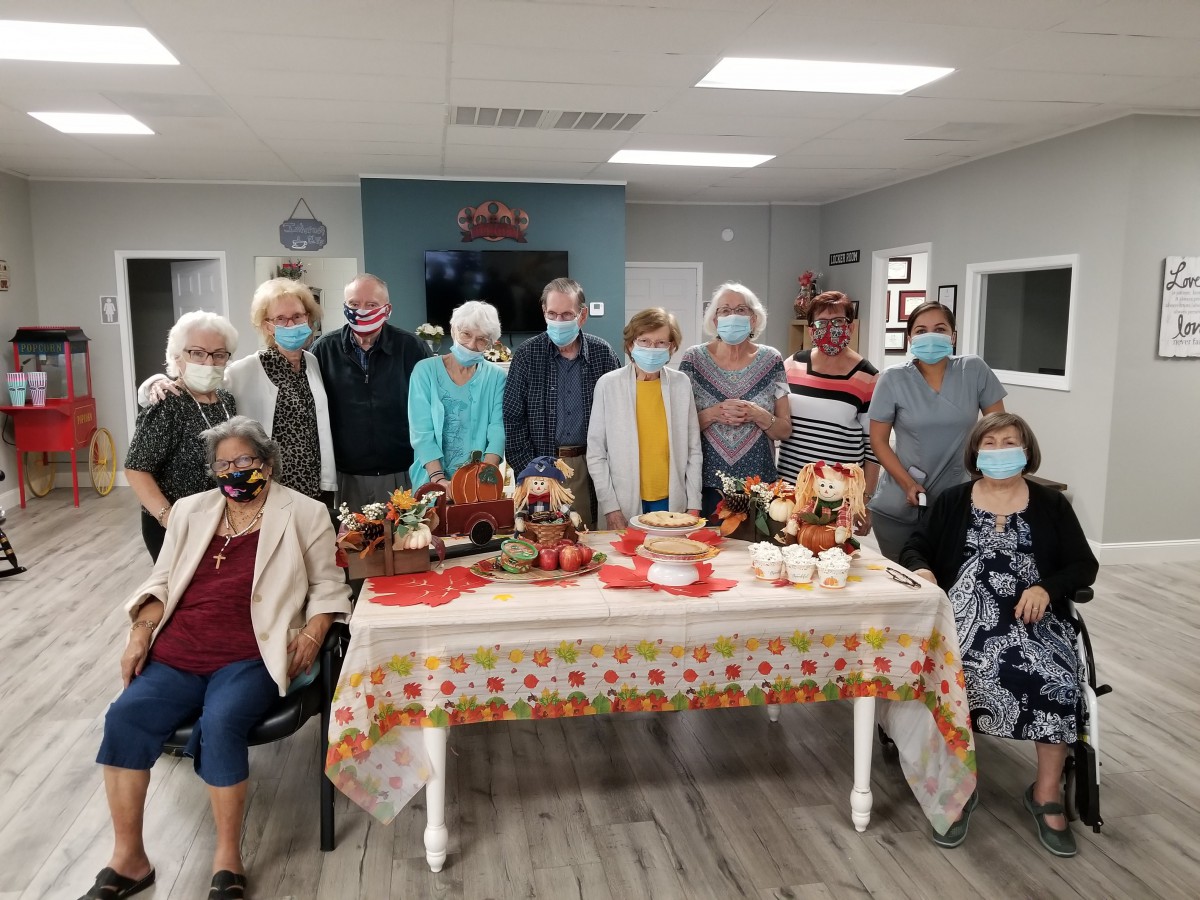 A group of people wearing masks gathered around a decorated table indoors.
