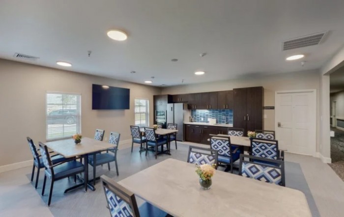 A modern dining area with tables, chairs, and a kitchen setup.