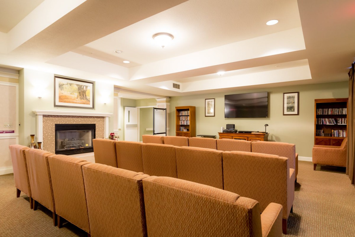 A cozy living room with sofas facing a television and a fireplace.