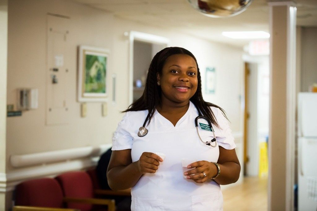 A nurse in a hospital corridor wearing a uniform.
