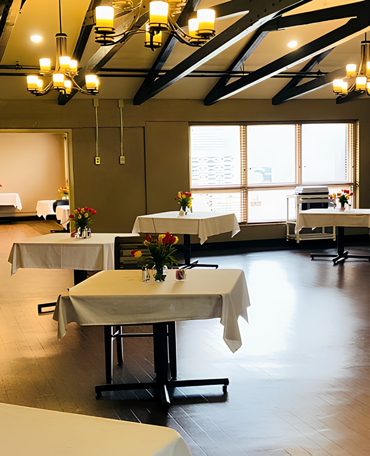 A spacious dining room with elegantly set tables and chandeliers.