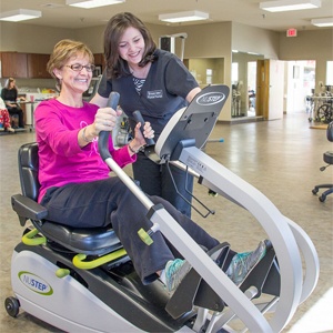 A woman receiving guidance from an instructor while using a specialized exercise machine.