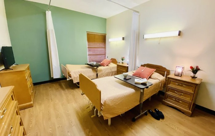 A clean and organized hospital room with two beds and medical equipment.