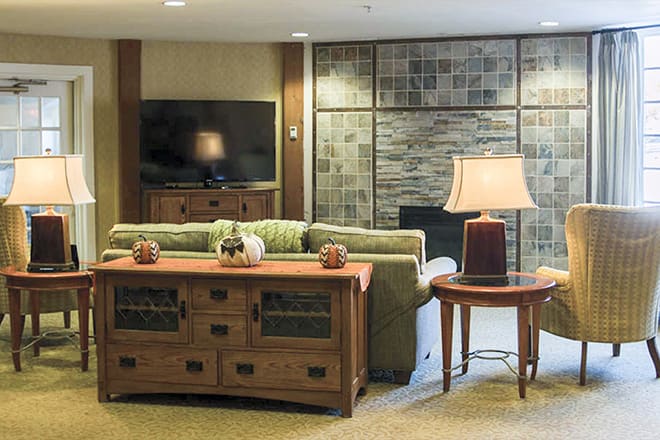 A cozy living room with a sofa, television, and decorative elements including a lamp and tables.