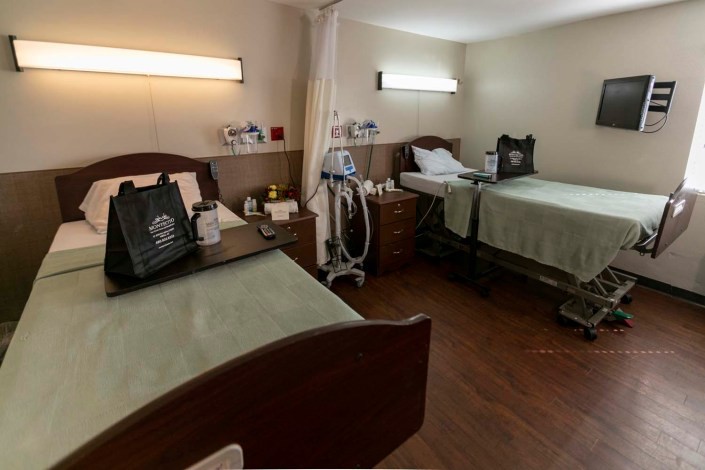 A hospital room with two beds, each accompanied by medical equipment and bedside tables.
