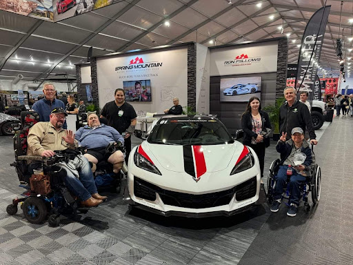 Visitors gather around a sleek sports car at an exhibition event.