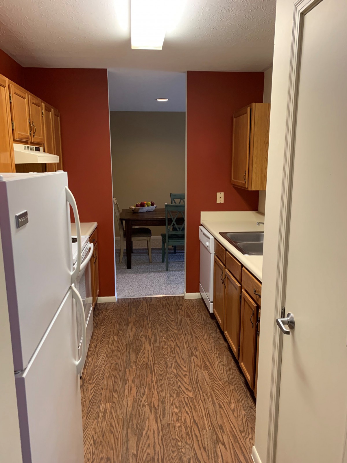A narrow kitchen with wooden cabinets and standard appliances.