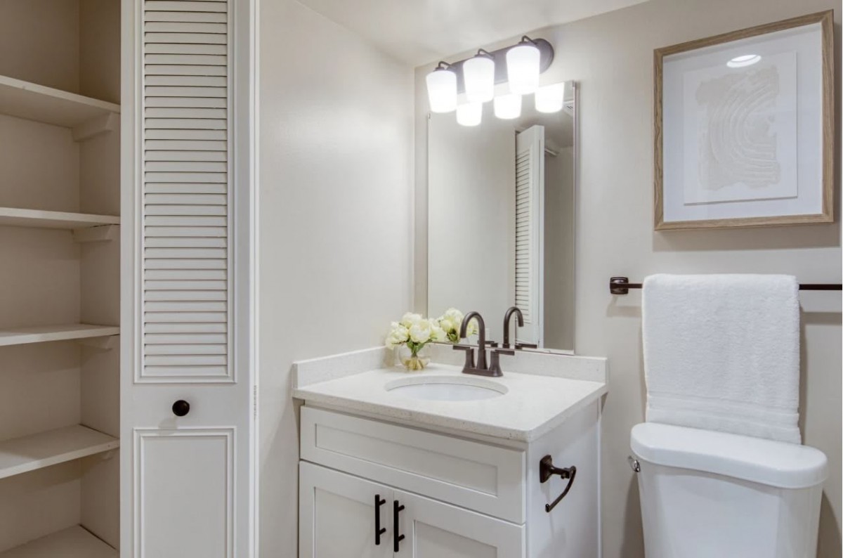 A modern bathroom with a white vanity and bright lighting.