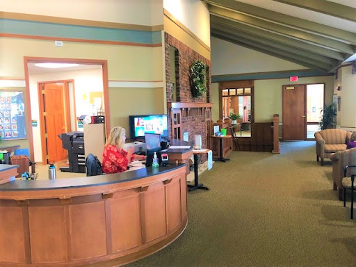 A welcoming reception area with wooden furniture and green walls, featuring a cozy atmosphere.