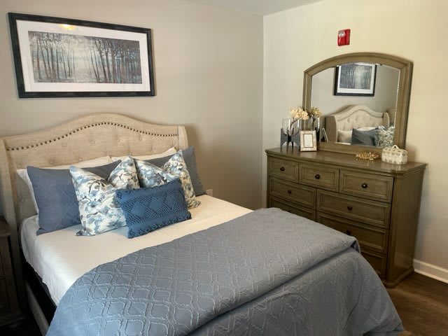 A cozy bedroom with a neatly made bed and a dresser with a mirror.