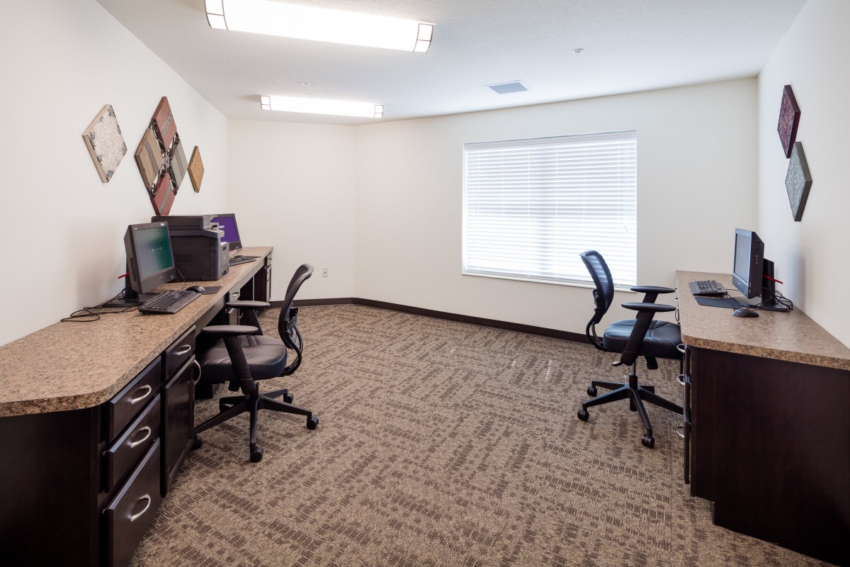 A modern office workspace with multiple desks and chairs arranged neatly.