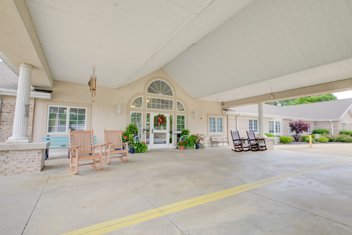 Covered entrance with rocking chairs and decorative plants.