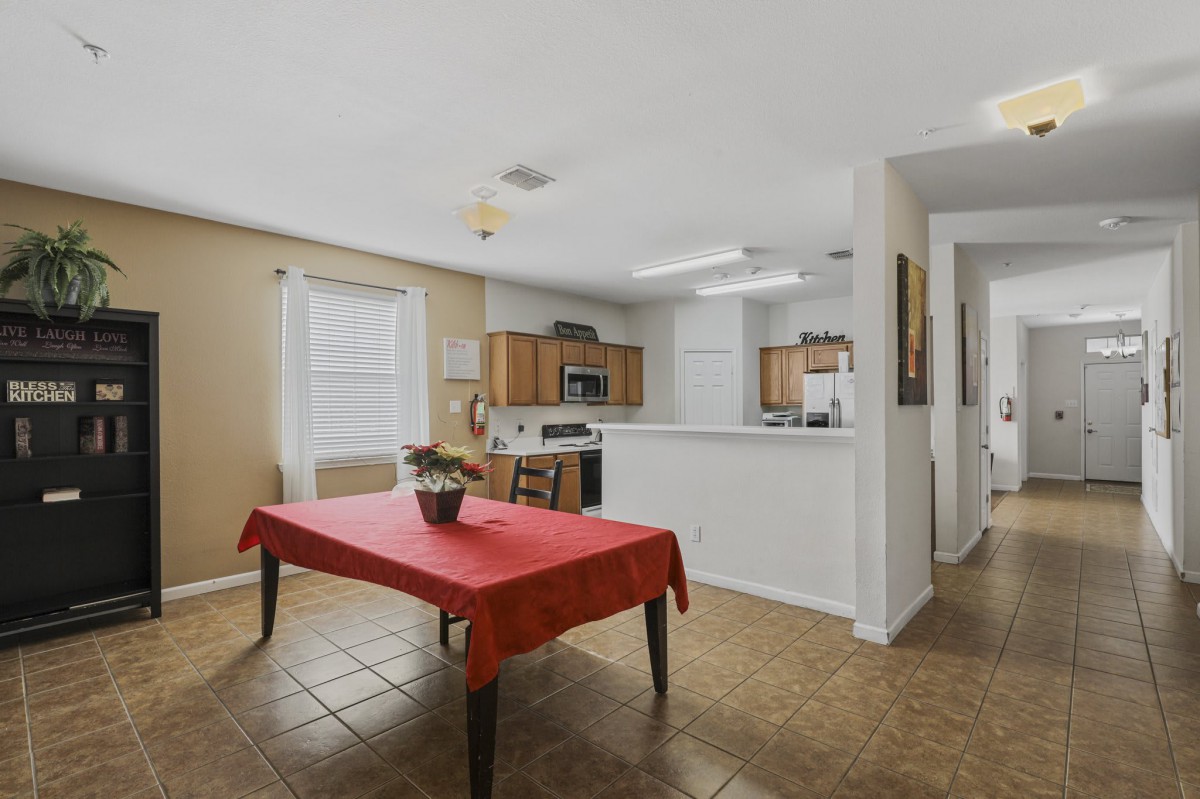 An open-layout kitchen and dining area featuring a red tablecloth on the dining table.