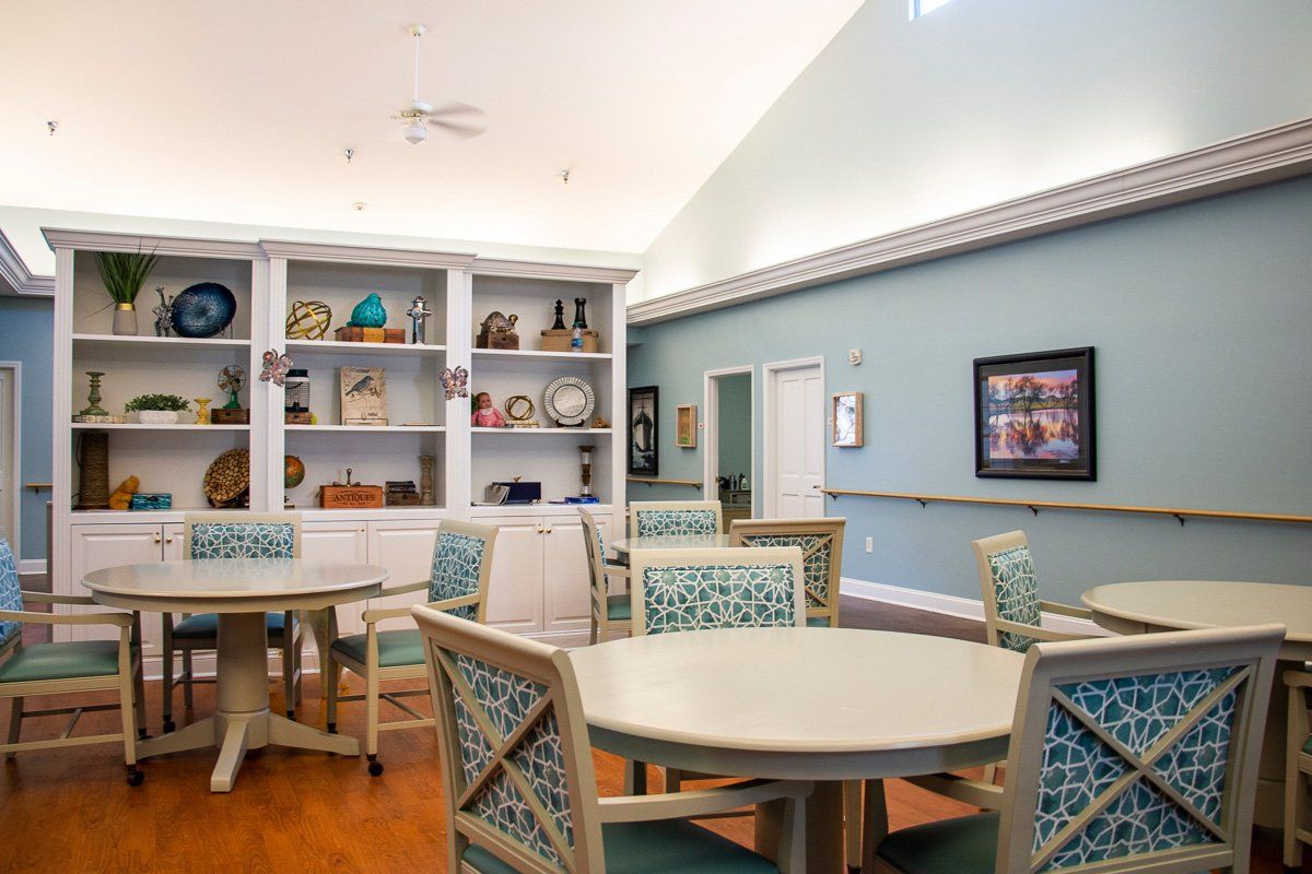 A cozy interior room with tables, chairs, and a decorated bookshelf.