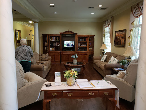 A cozy living room featuring comfortable sofas and a wooden bookcase, with a television in the background.