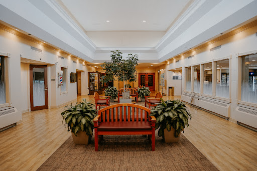 A spacious and welcoming lobby featuring wooden benches, indoor plants, and bright lighting, perfect for relaxation.