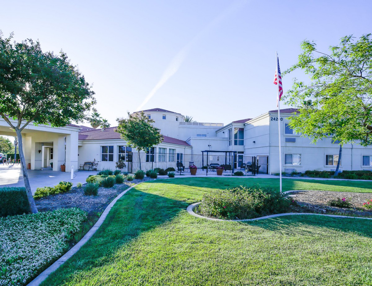A sunny day view of a large building with a well-maintained lawn and greenery.