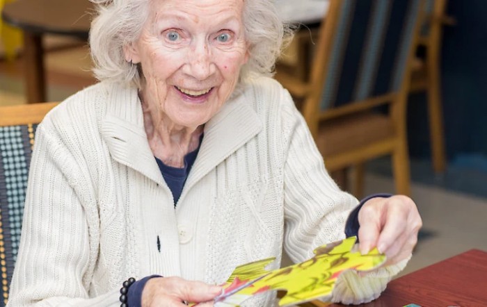 An elderly woman engaging in a crafting activity indoors.