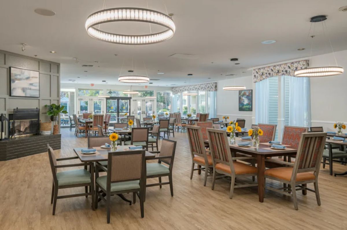 A spacious dining area with neatly arranged tables and chairs, featuring modern lighting fixtures.