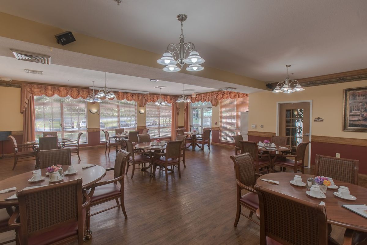 Spacious dining area with wooden tables and chairs, illuminated by chandeliers.