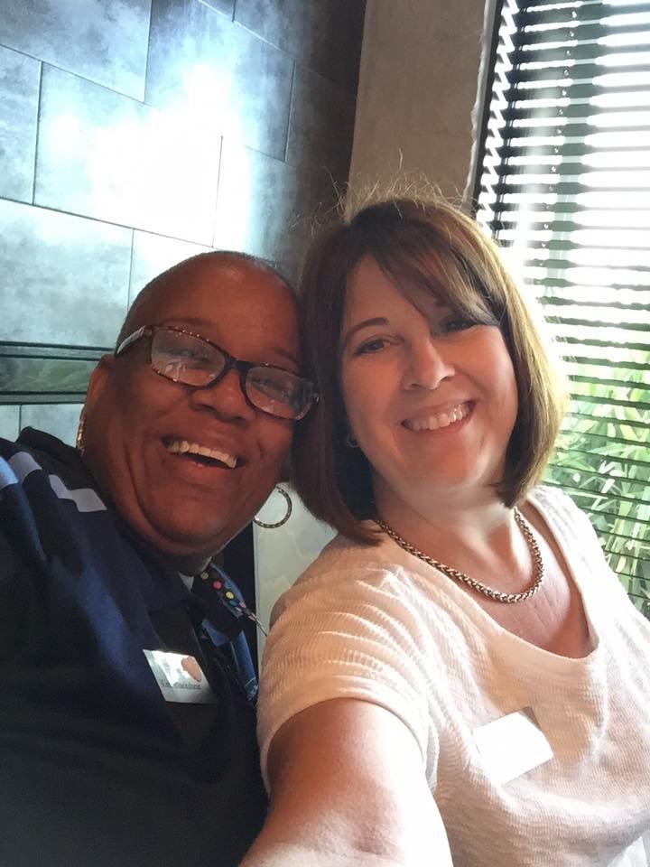 Two friends smiling for a selfie indoors.