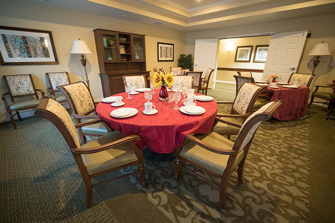 A cozy dining room with a round table set for a meal.