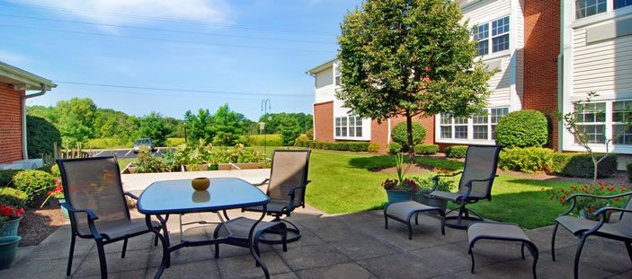 A sunny backyard patio with outdoor furniture and a landscaped garden.