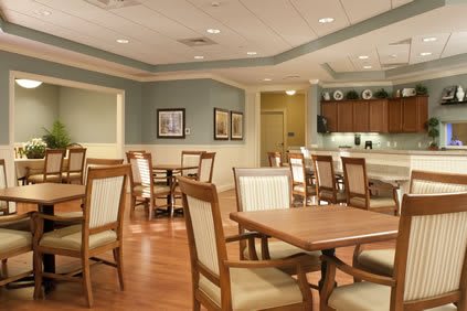 A spacious dining area with wooden tables and chairs, featuring warm lighting and elegant decor.