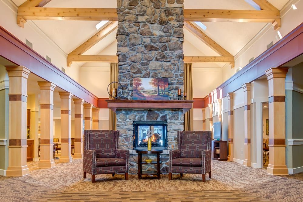 A cozy lobby with a stone fireplace and comfortable armchairs, accented by wooden beams.