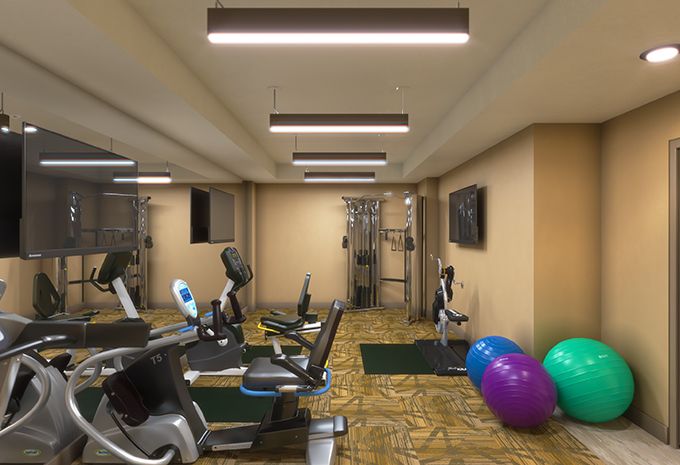 A well-equipped gym with treadmills, exercise bikes, and stability balls in a spacious indoor setting.