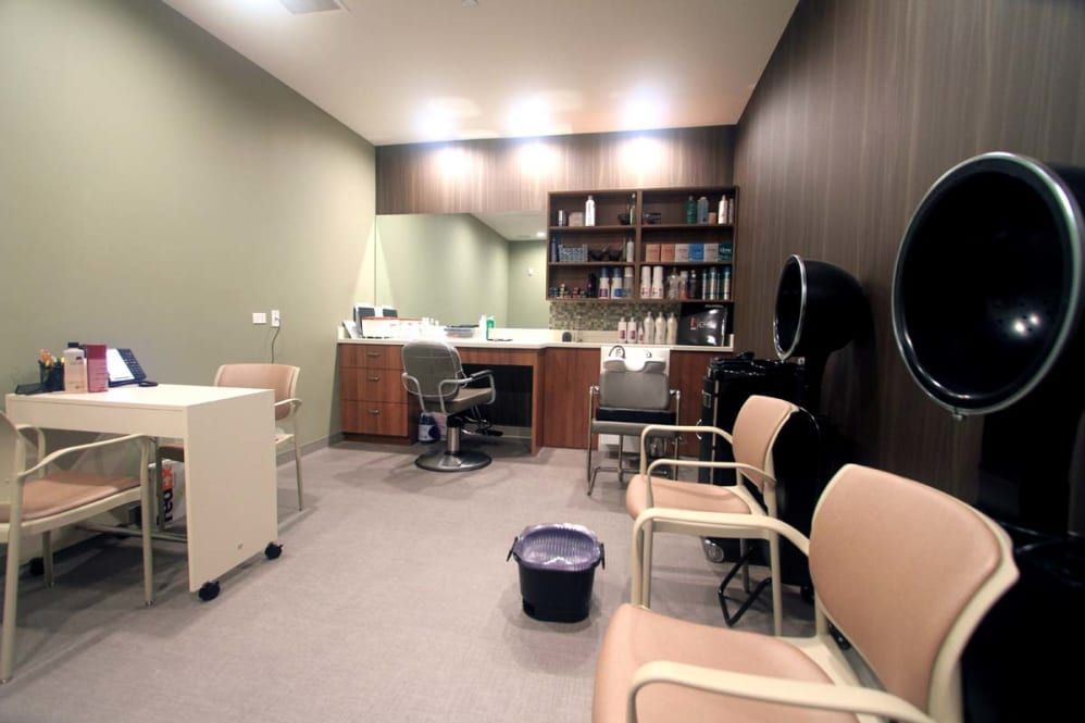 A modern salon interior with chairs, a mirror, and shelves stocked with hair products.