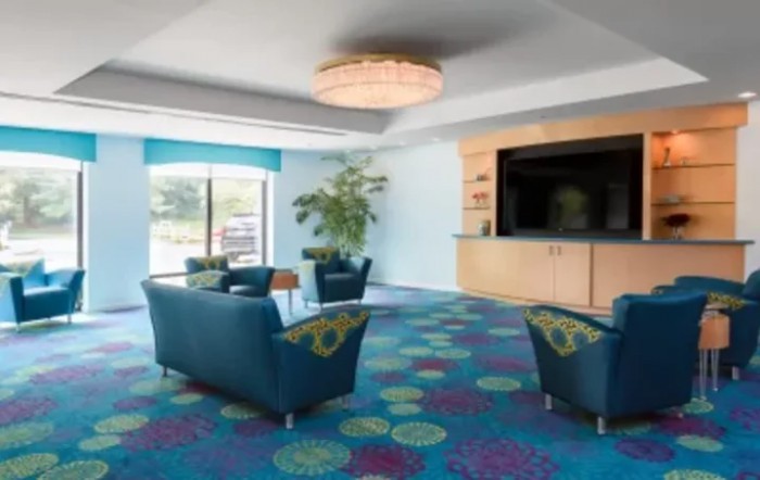 A modern hotel lobby with comfortable seating and a large television.