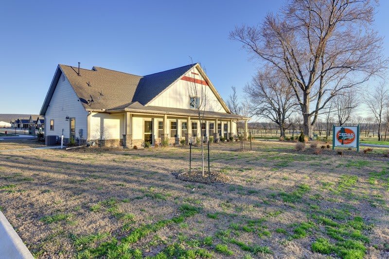 A charming rural house with a spacious yard and trees, bathed in sunlight.