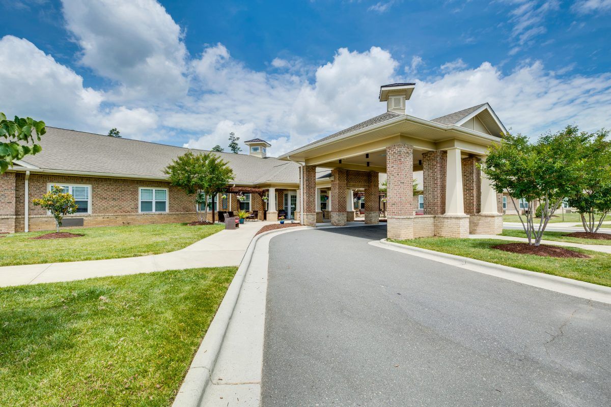 A view of a building with a driveway and entrance under a partly cloudy sky.