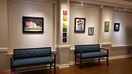 A view of an art gallery featuring various paintings and comfortable seating.