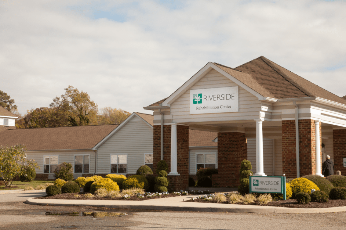 A healthcare clinic building with a parking lot in front, captured during the daytime.