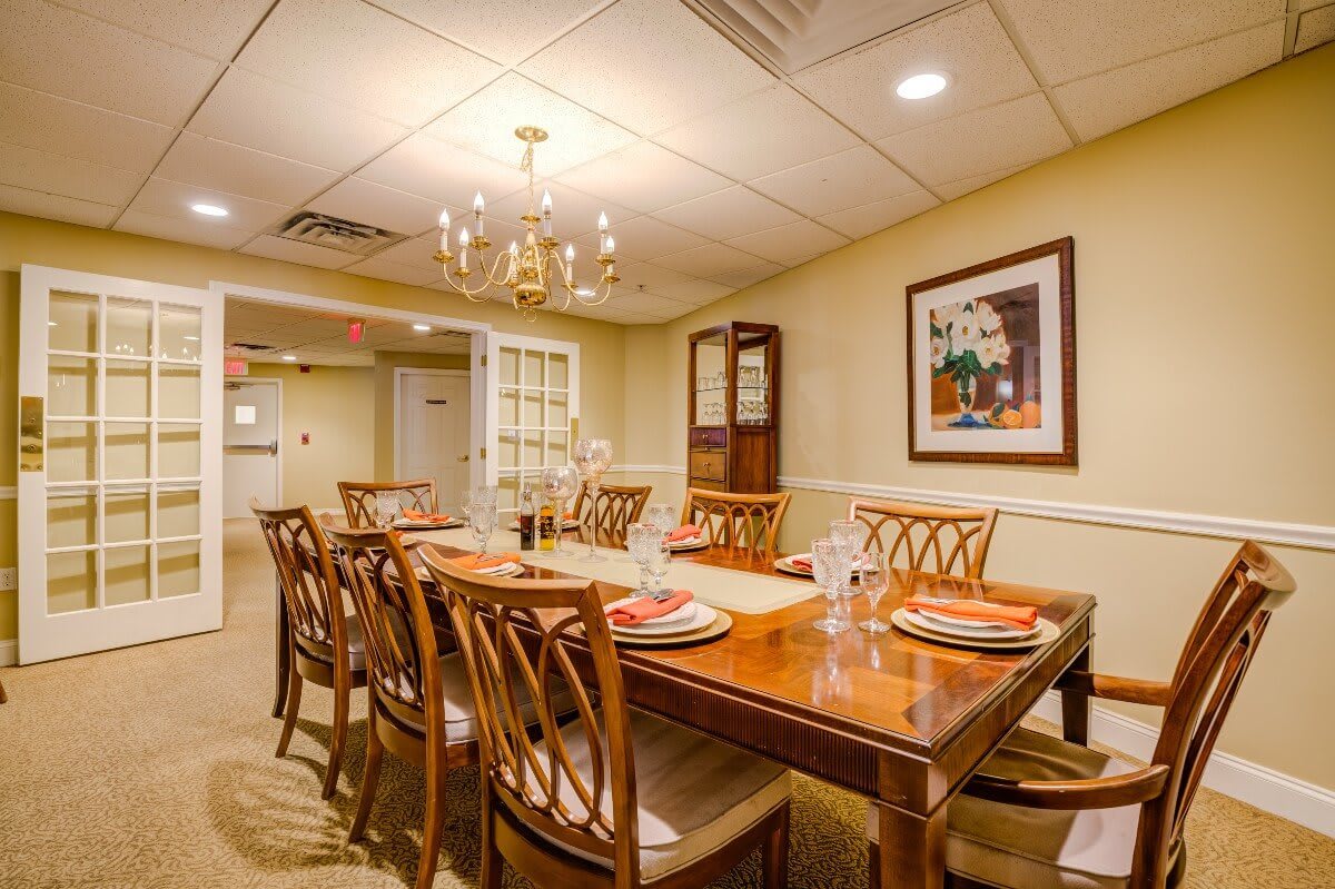 A well-appointed dining room with a wooden table set for a meal, surrounded by matching chairs and illuminated by an elegant chandelier.