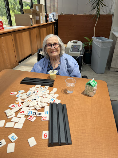 An elderly person enjoying a game with tiles at a table.
