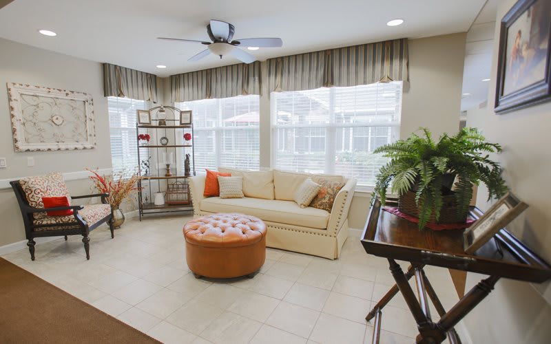 A cozy living room with a comfortable sofa, round coffee table, and large windows with drapes.