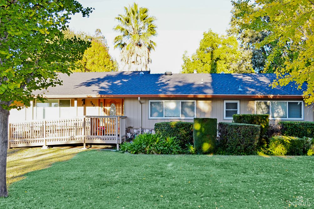 A cozy suburban house with a well-maintained lawn and surrounding trees.
