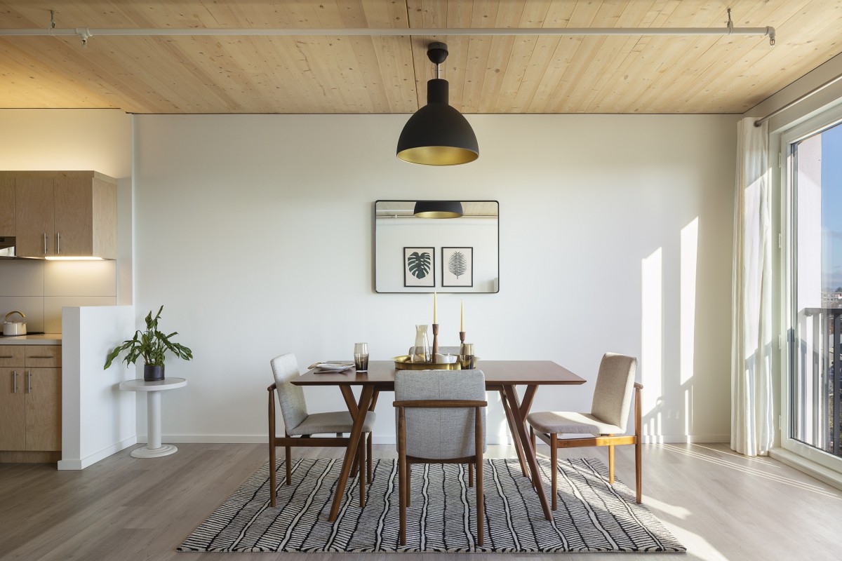 A modern dining room with a minimalist design, featuring a wooden table, chairs, and decorative elements.
